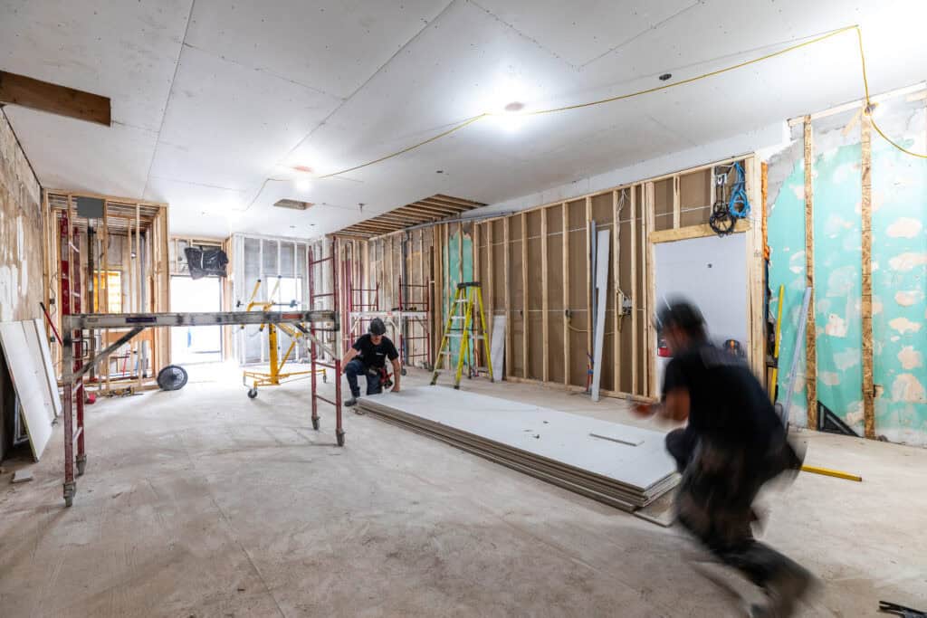 Construction workers installing drywall at a V2R Group project.