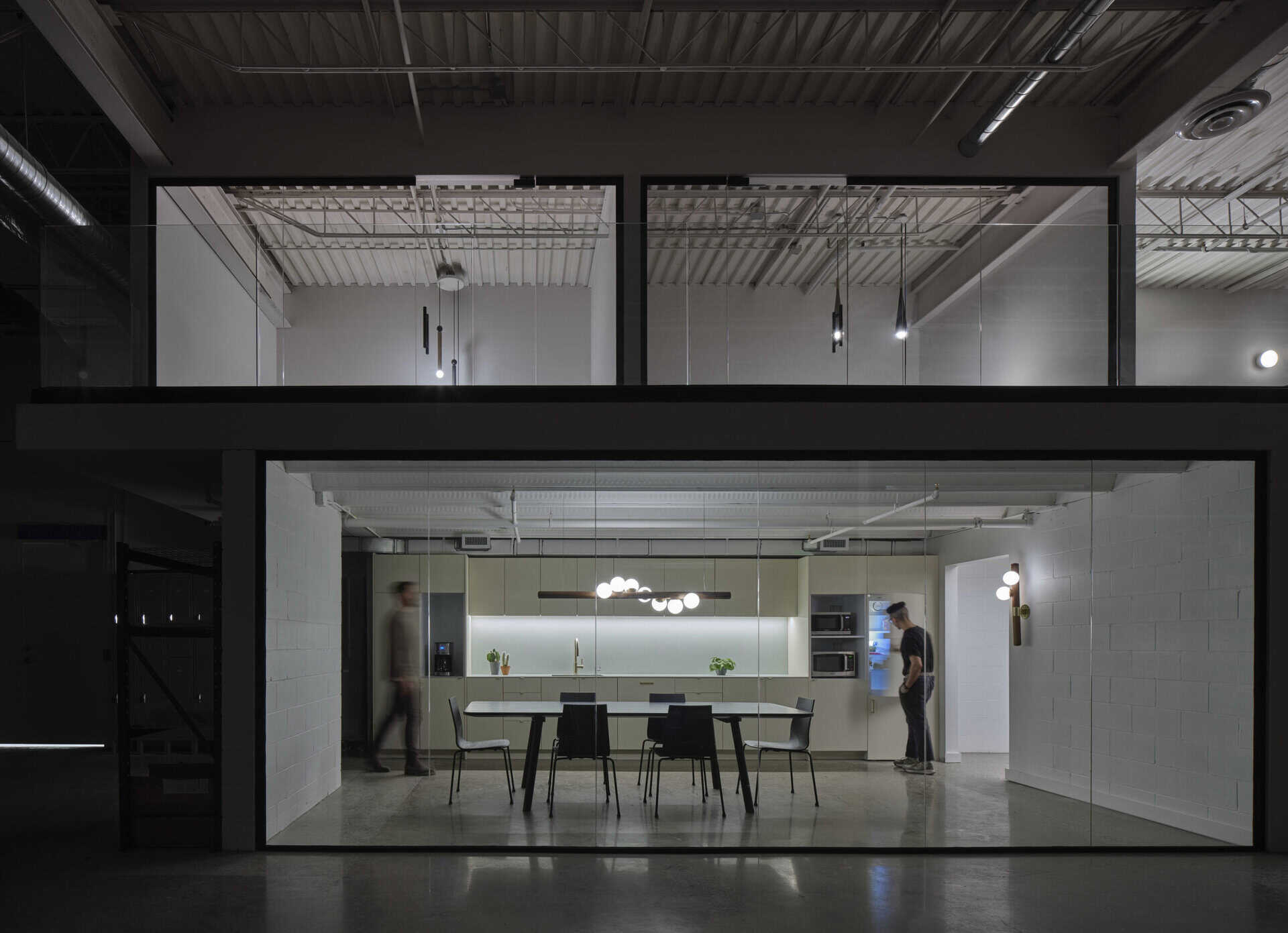 Office interior with glass walls, modern furniture, and contemporary lighting.
