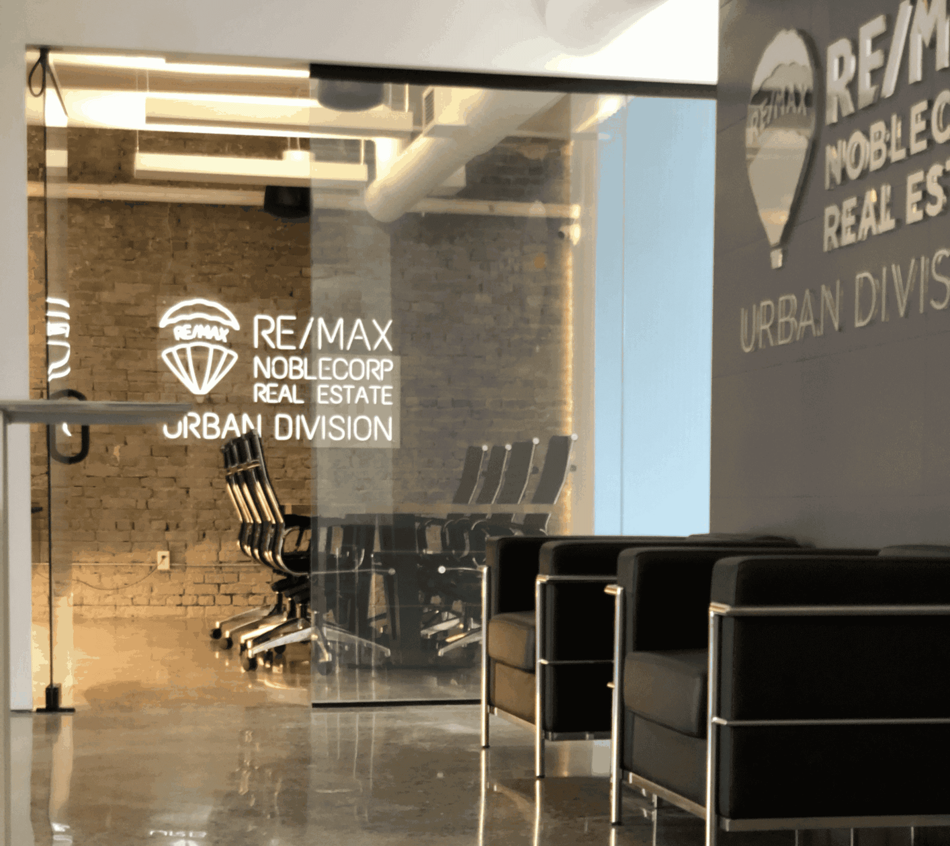 Modern real estate office with seating area and branding.