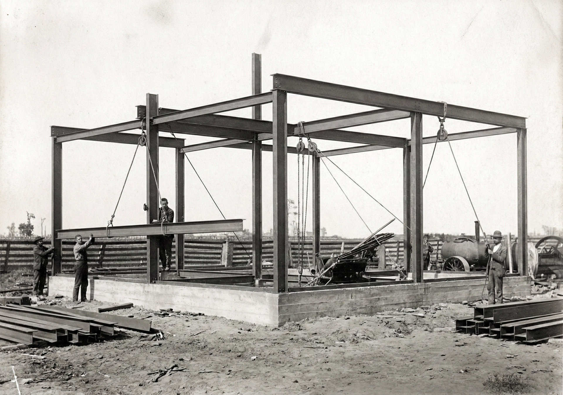 Construction site with steel framework and workers assembling the structure.