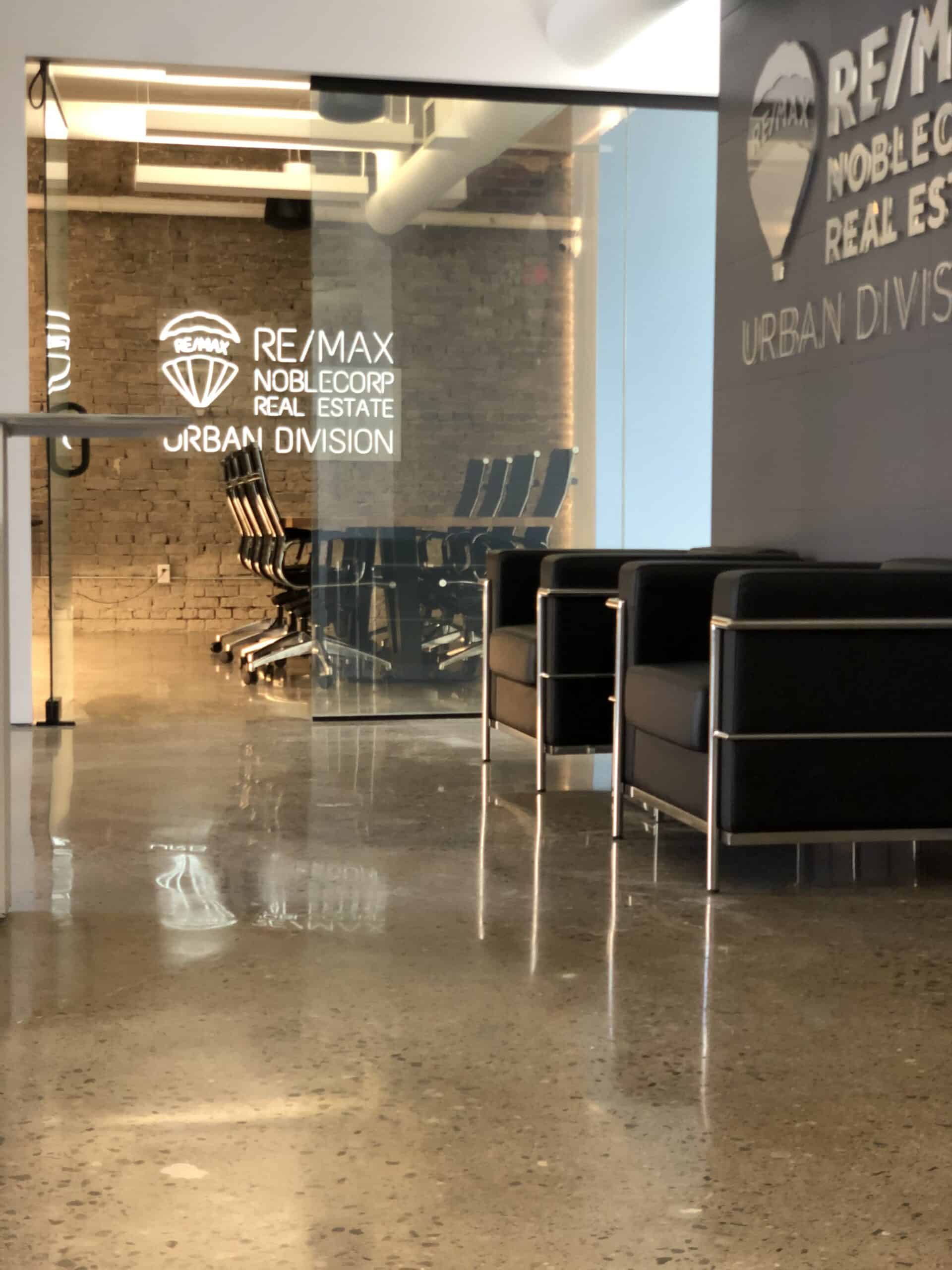 Modern real estate office with seating area and glass conference room.